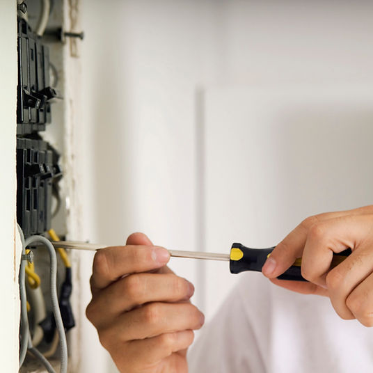 electrician working on panel with screwdriver
